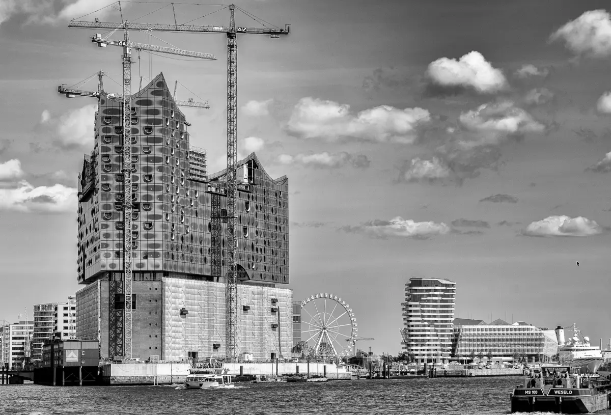 Die Elbphilharmonie im Rohbau, umgeben von Baukränen, davor der Kaispeicher
